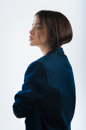 Ready to act. Beautiful young focused woman standing in profile while looking straight and wearing jacketの写真素材