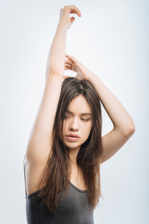 Good morning. Beautiful adorable brunette woman rising her hands while gazing aside and getting ready for a new dayの写真素材