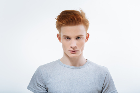 Ginger good looking earnest guy hypnotizing with look while song on white background and staring straightの写真素材