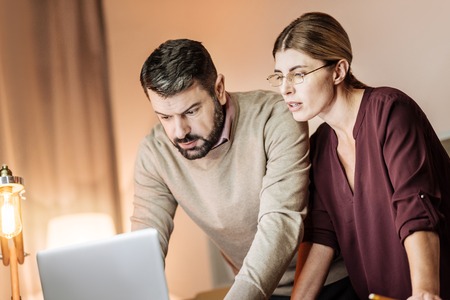 Need your advice. Handsome bearded man wrinkling forehead and bowing head while talking to his colleagueの写真素材
