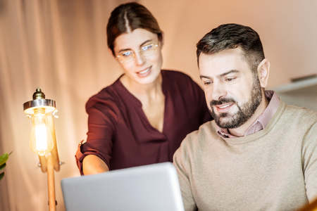 It is best variant. Silhouette of pretty woman that expressing positivity and standing near her colleague while pointing at laptopの写真素材