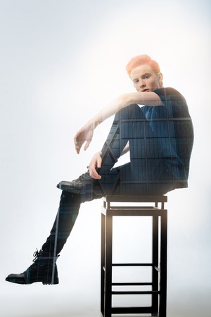 Frizz in this pose. Serious professional concentrated model sitting on the chair posing and looking straight.の写真素材