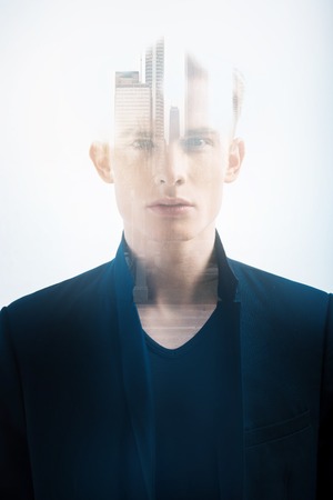 City life. Concentrated confident successful man looking straight standing and thinking in the specious bright room.の写真素材