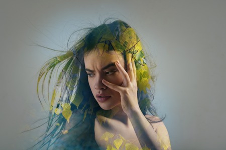 Sprig mood. Creative emotional beautiful girl staying in the room touching her face and looking aside.の写真素材