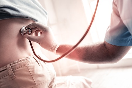 Do not breath for a second please. Close up of male physician checking his patient health and listening to his breathing at a clinic.の写真素材