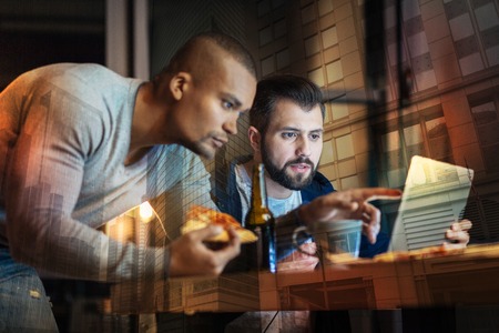 Strange information. Serious young attentive friends looking at the information on the screen of...