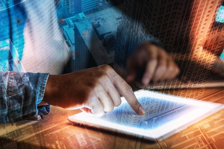 One touch. Calm responsible employee touching the screen of a modern tablet with a help of one finger while sitting alone and workingの写真素材