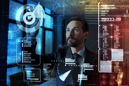 Good results. Smart experienced elegant programmer looking confident while touching the transparent screen and working at the modern program of protecting personal informationの写真素材