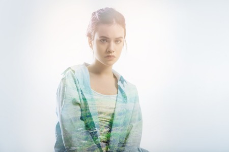 Quiet student. Concentrated attentive diligent student sitting quietly on the chair and looking calm while listening to her experienced professional teacherの写真素材