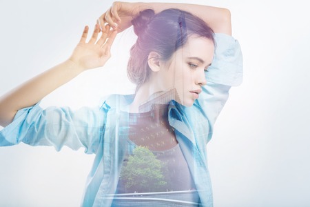 New view. Young curious beautiful woman standing on the bridge with her arms above her head and thoughtfully looking downの写真素材