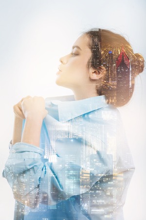 Changing clothes. Pleasant young beautiful putting on a clean blouse and feeling good while standing in front of a mirror and looking at her reflectionの写真素材