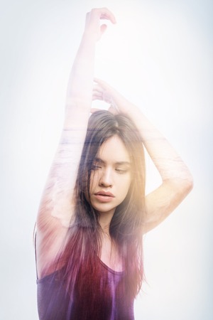 Long hair. Calm serious young woman putting her hand up while doing usual exercises after spending too much time in front of a laptopの写真素材