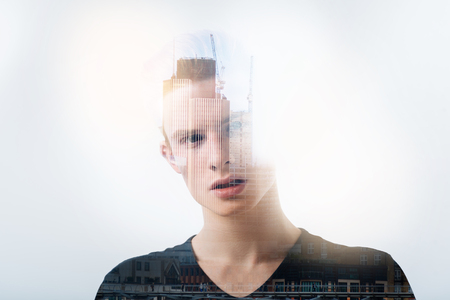 Outraged. Emotional young handsome man standing against the urban background and feeling angry while thinking about an unfair situation at the universityの写真素材