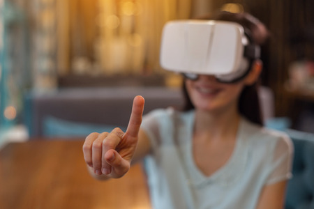 VR app. Selective focus of female hand showing index finger while pleasant pleased woman posing at...