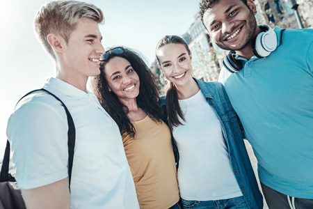 True friendship. Happy positive nice students standing together and looking at you while being in a positive moodの写真素材