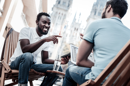 What are your thoughts. Best mates sitting outdoors and smiling while enjoying a pleasant conversation together.の写真素材