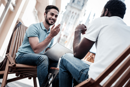 Best teammates ever. Low angle shot of happy coworkers gesturing and smiling cheerfully while sitting in a cafe and talking.の写真素材