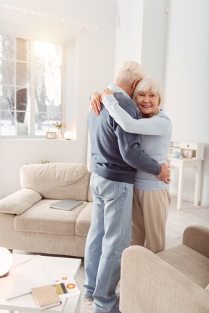 Hold me close. Happy elderly woman posing for the camera during the dance with her husband while hugging him tightlyの写真素材
