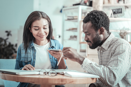 Common project. Nice delighted smart student sitting together in the cafe and studying while preparing a projectの写真素材