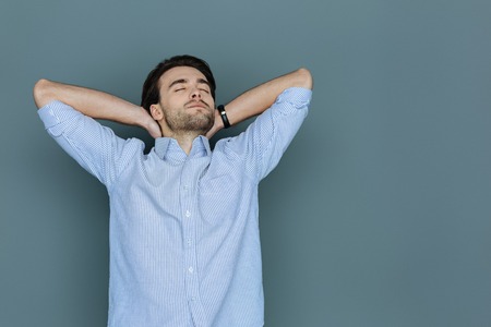 Time to relax. Delighted pleasant dreamy man closing his eyes and sleeping while resting after workの写真素材