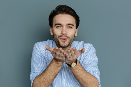 Delighted happy good looking man holding his hands together and sending you kisses while expressing feelingsの写真素材