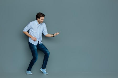 Professional musician. Positive nice happy man standing and looking at his guitar while looking at itの写真素材