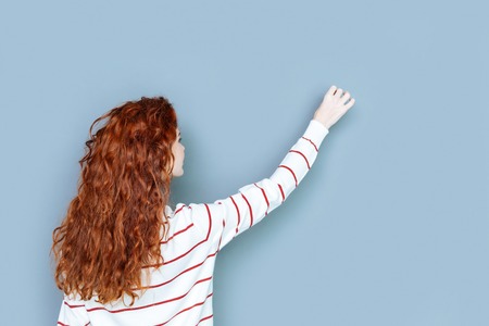 Female teacher. Positive nice happy woman turning to the wall and writing on it while giving a lessonの写真素材
