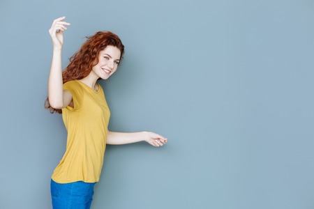 Great mood. Cheerful positive joyful woman holding her hand up and turning her face to you while smilingの写真素材