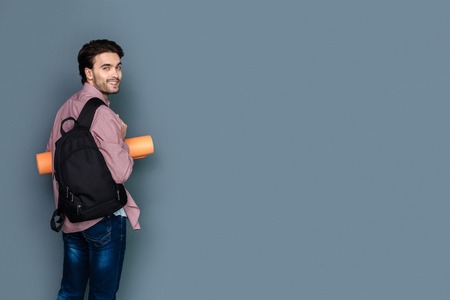 Walking tour. Joyful handsome young man wearing a rucksack and smiling to you while having a walking...