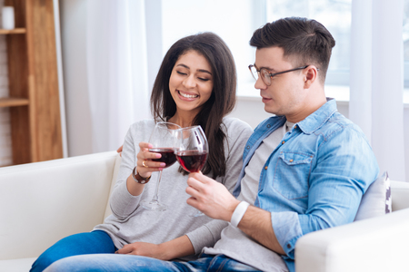 Jolly jovial couple holding glasses with wine while smilingの写真素材