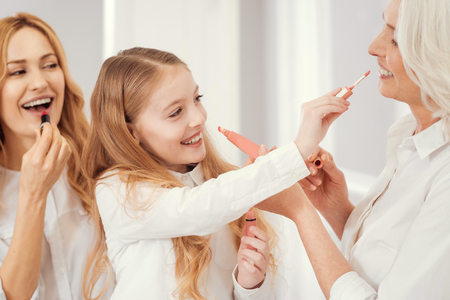 Excited three generations of women grinning broadly while having fun in a family circle and...