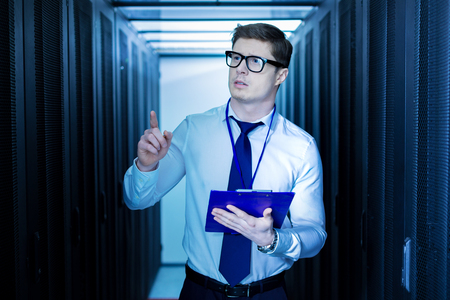 Handsome unsmiling operator holding a folder and pointing with his finger
