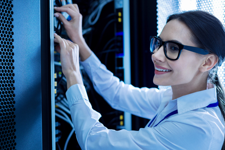Exuberant smart woman working in a service cabinet and repairing wires
