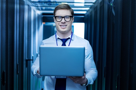 Cheerful young operator smiling and holding a laptop