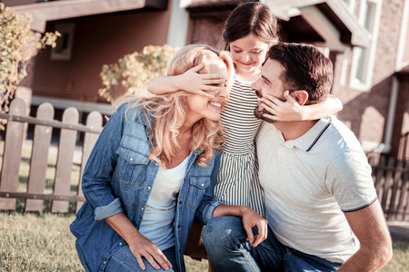Best parents. little pretty satisfied girl spending time with their parents standing and hugging her them.の写真素材