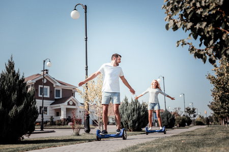 I will lead. Joyful interested happy couple spending time together having fun riding on the self-balancing scooter.の写真素材