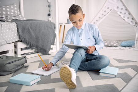 Online learning. Focused afro american boy performing task while using tablet