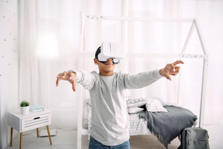 Pretty afro american boy wearing VR headset while stretching hands