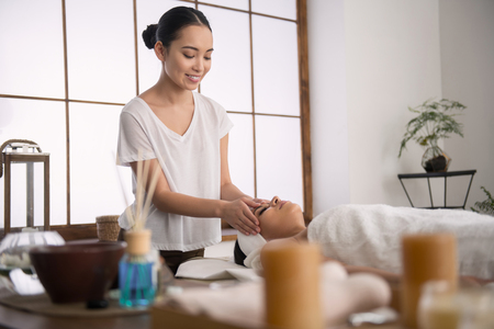 Favourite job. Cheerful young masseuse smiling to her client while enjoying her jobの写真素材