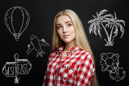 Dreamy girl. Pretty young girl smiling and looking into the distance while standing alone and dreaming about travelling by planeの写真素材