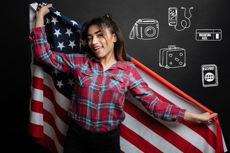 Happy American. Young emotional tourist feeling happy and holding a big American flag while visiting the USA for the first timeの写真素材