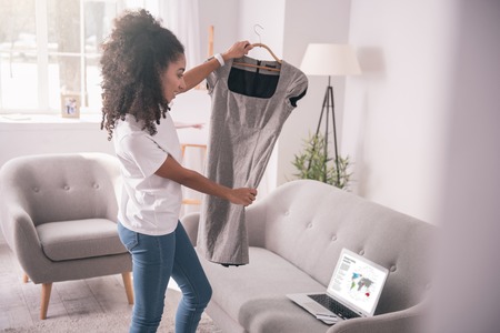 Getting ready. Pretty young woman holding a dress while getting ready to go to workの写真素材