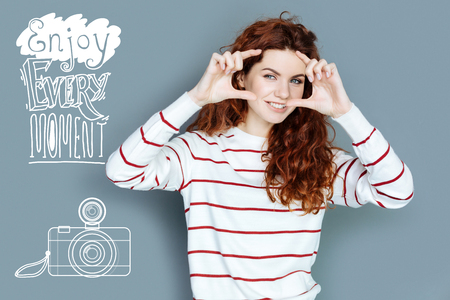 Taking photos. Cheerful young emotional tourist enjoying her holidays and taking photosの写真素材