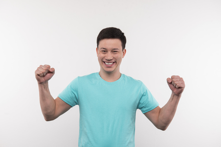 Personal success. Joyful young man holing his hands up while thinking about his personal successの写真素材