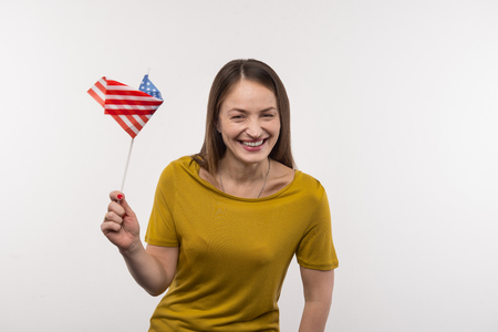 American citizen. Joyful nice woman holing the US flag while expressing her patriotic feelingsの写真素材