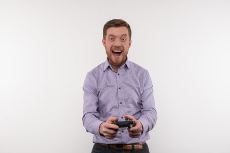 Game addiction. Joyful attractive man playing video games while being games addictedの写真素材