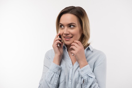 In touch. Delighted nice woman putting the phone to her ear while answering the callの写真素材