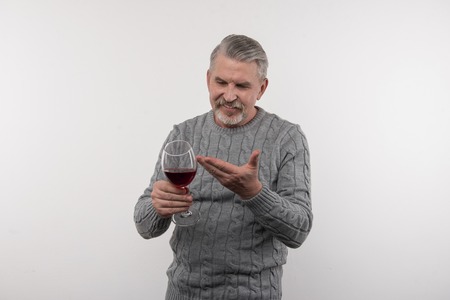 Alcohol addiction. Happy positive man pointing at the glass of wine while intending to drink itの写真素材