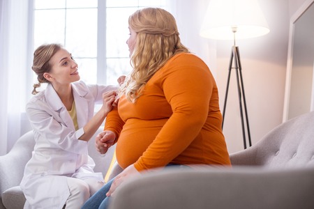Good results. Alert professional nutritionist talking with a fat woman and measuring herの写真素材