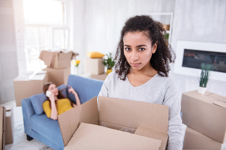 Mad at you. Curly-haired young girl looking at the camera with annoyed expression and carrying a...